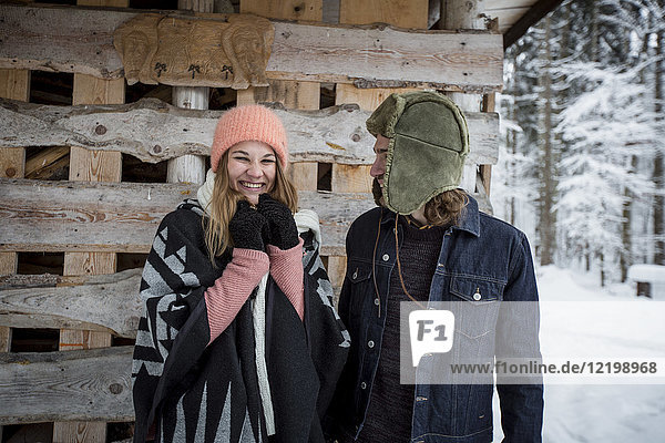 Portrait of happy couple in front of wood pile outdoors in winter