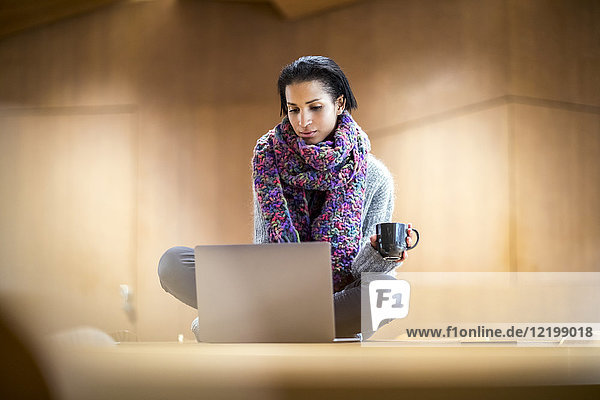 Porträt einer modischen jungen Frau mit einer Tasse Kaffee auf dem Konferenztisch mit Laptop