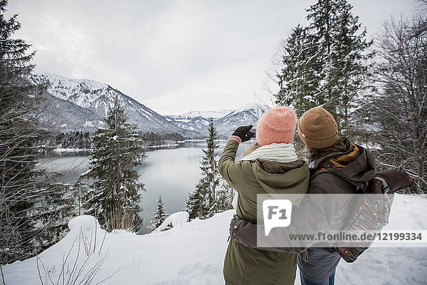 Couple taking a picture in alpine winter landscape with lake
