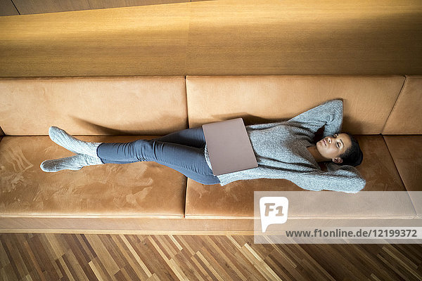 Frau mit Laptop entspannt auf der Couch