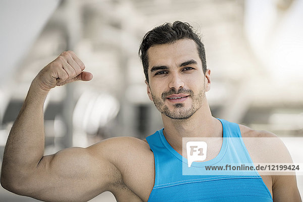Porträt eines Mannes  der in der Stadt trainiert und Muskeln beugt.
