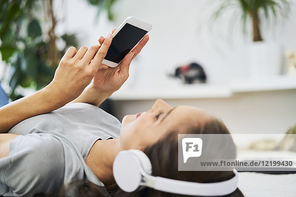 Young woman lying on the floor with headphones and cell phone
