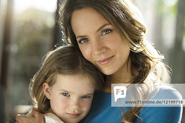 Porträt der lächelnden Mutter mit Tochter vor dem Fenster