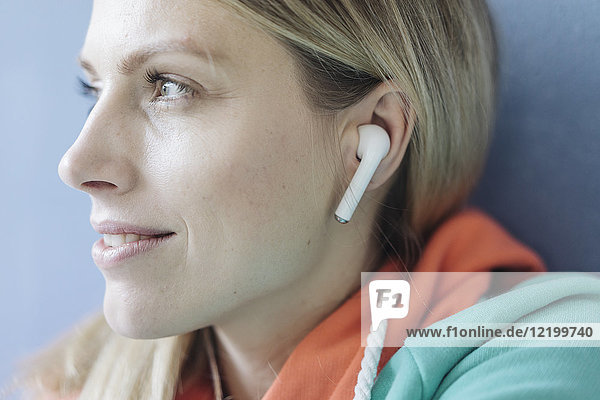 Portrait of smiling woman listening music with wireless earphones  close-up
