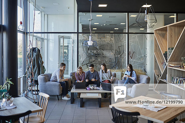 Gruppe von Freunden sitzen zusammen in einem Café mit Laptop