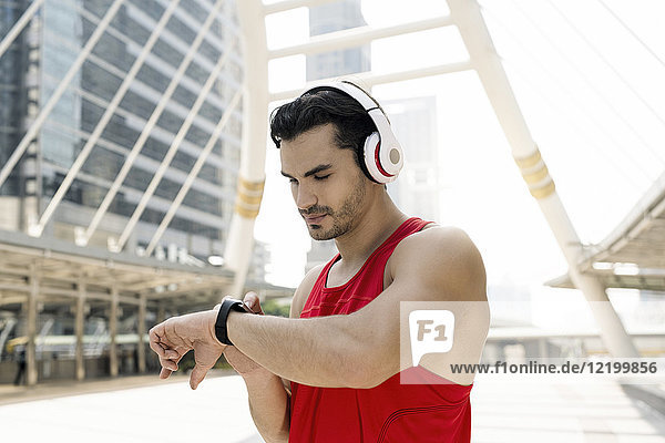 Athlet mit Kopfhörer  der seine Smartwatch überprüft