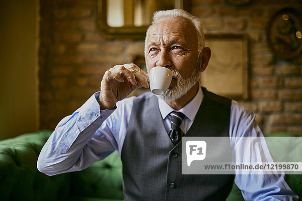 Eleganter älterer Mann beim Kaffeetrinken im Café
