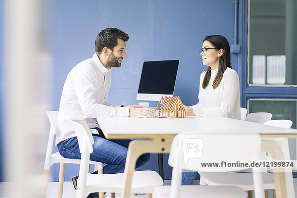 Mann und Frau im Gespräch mit Architekturmodell auf dem Tisch