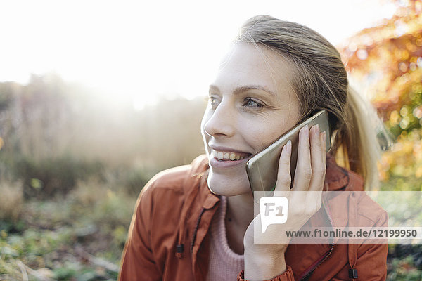 Porträt einer jungen Frau am Telefon im Herbstpark