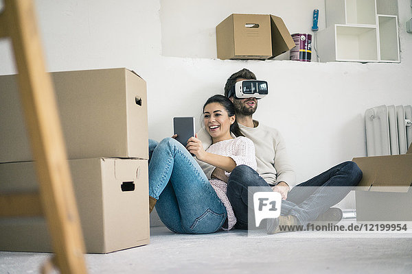 Paar sitzend im neuen Zuhause mit Mann mit VR-Brille