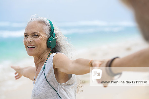 Portrait of beautiful smiling senior woman dancing on beach