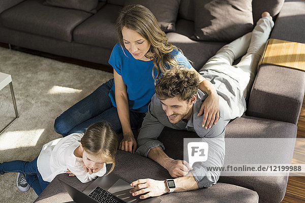 Family using laptop on sofa at home