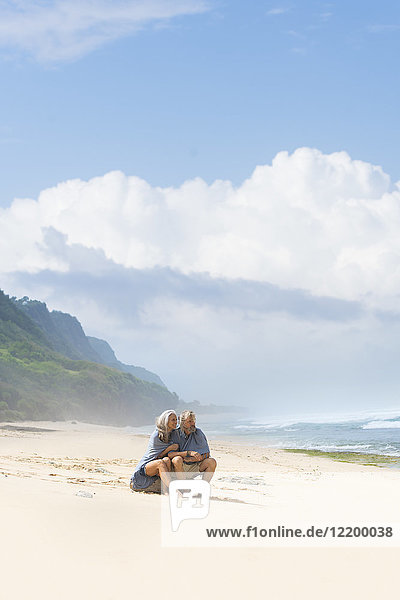 Seniorenpaar am Strand sitzend  in eine Decke gehüllt