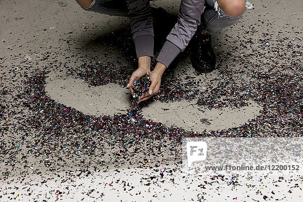 Frauenhände beim Sammeln von Konfetti vom Boden