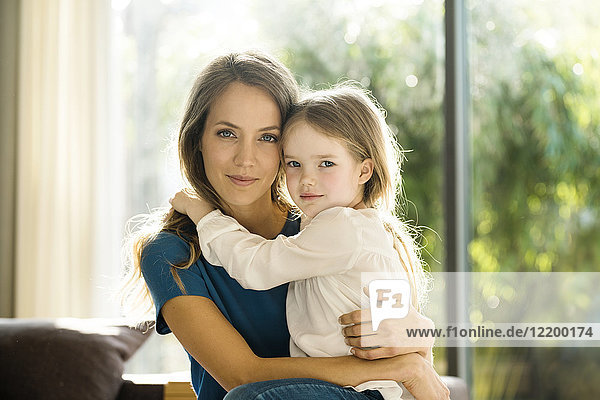 Portrait of smiling mother holding her daughter at home
