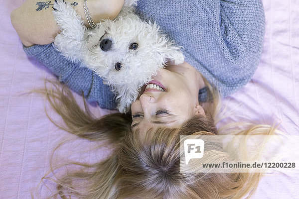 Happy woman lying on bed with her dog