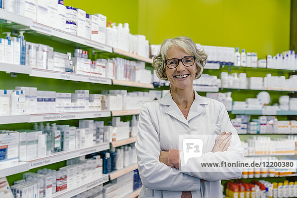 Portrait of smiling pharmacist at shelf with medicine in pharmacy
