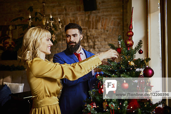 Elegant couple decorating Christmas tree