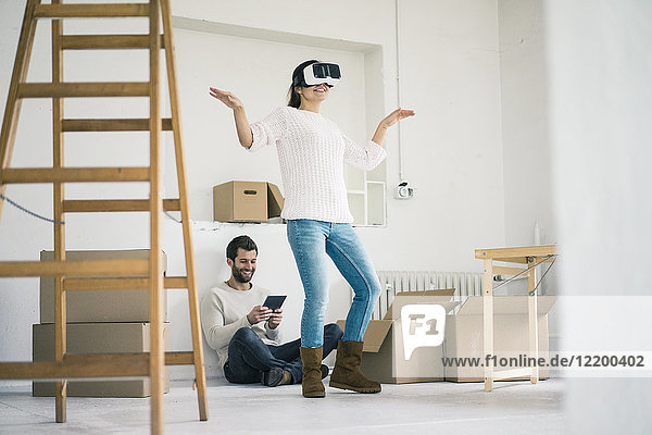 Paar in neuem Zuhause mit Frau mit VR-Brille