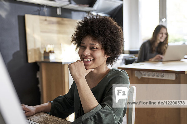 Happy young woman using computer in modern office