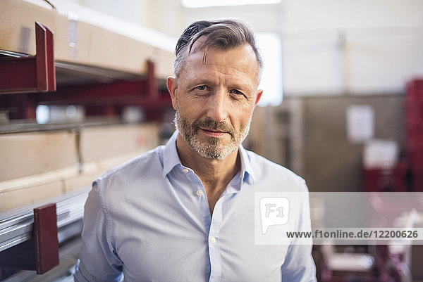 Portrait of confident mature businessman in factory storeroom