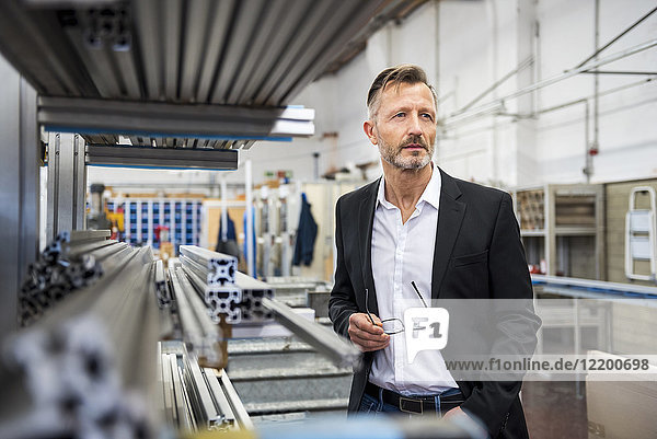 Mature businessman in factory thinking