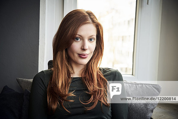 Portrait of redheaded woman in front of window at home