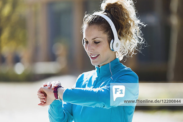 Sportive young woman with headphones checking the time
