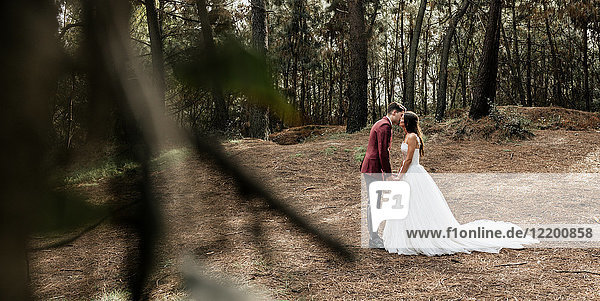 Braut und Bräutigam küssen im Wald