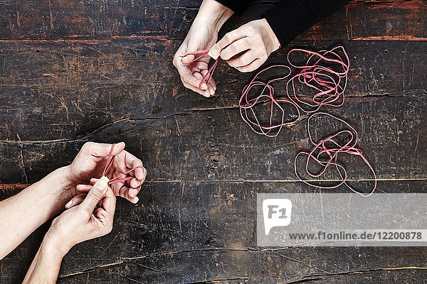 Hands of man and woman playing with rubber bands  top view