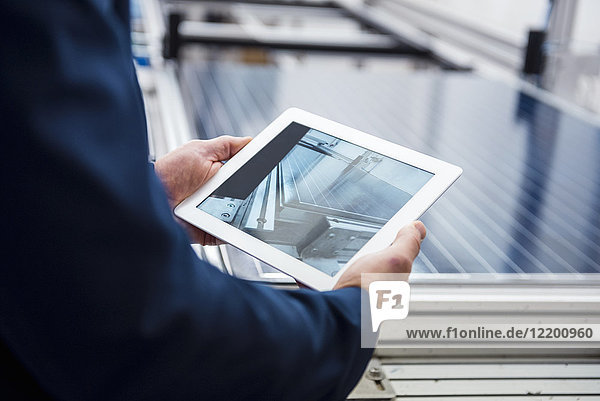 Businessman in solar factory holding tablet