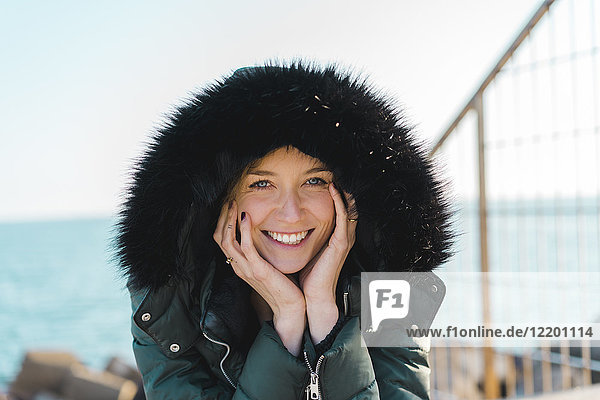 Porträt einer glücklichen Frau mit Kopf in der Hand in Kapuzenjacke