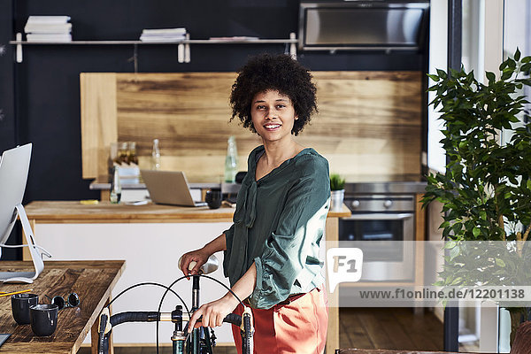Portrait of smiling young woman with bicycle in modern office