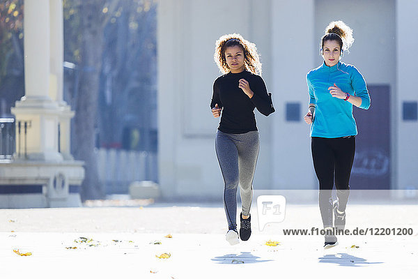 Two focused young women running listening to music