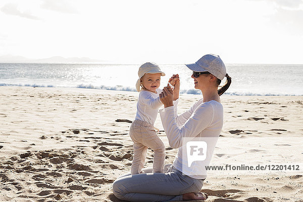 Glückliche Mutter mit kleiner Tochter am Strand