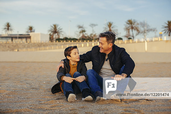Lächelnder Vater umarmt Sohn am Strand