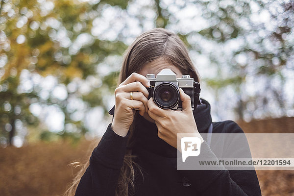 Portrait of young woman taking photos in autumn
