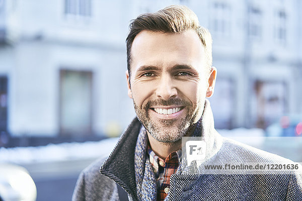 Porträt des lächelnden Mannes auf der Stadtstraße im Winter