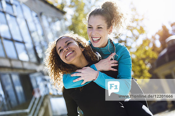 Happy young woman carrying friend piggyback