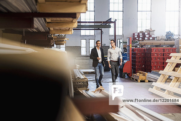 Two businessmen walking in factory storeroom