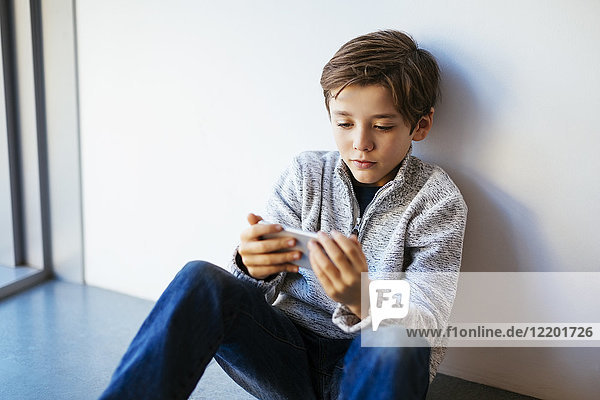 Boy sitting on floor looking at cell phone