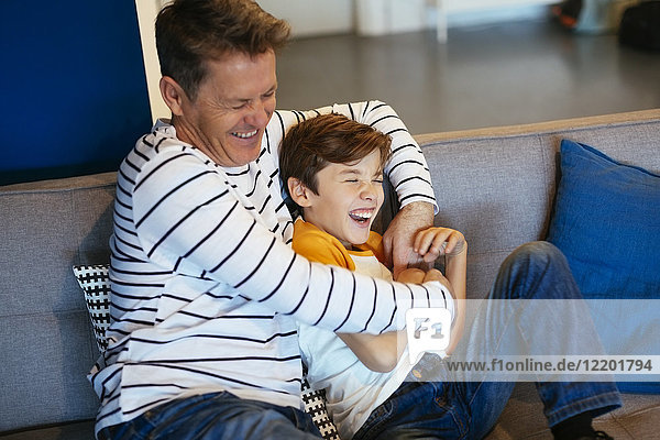 Carefree father and son having fun on couch at home