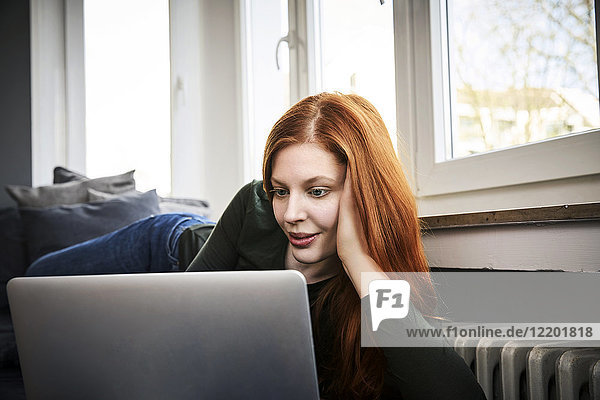 Portrait of redheaded woman using laptop at home