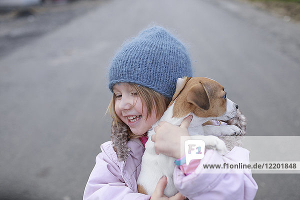Glückliches kleines Mädchen mit Jack Russel Terrier Welpe