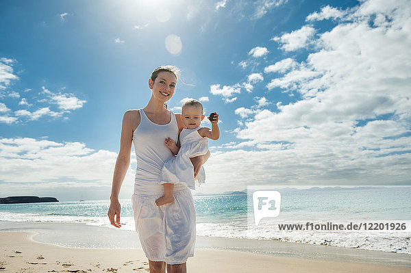 Mutter geht mit kleiner Tochter am Strand spazieren
