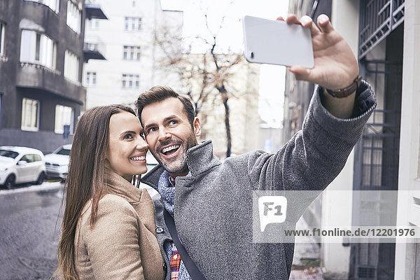 Happy couple taking selfie in the city