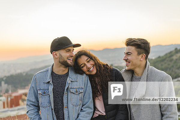 Porträt von drei glücklichen Freunden auf einem Hügel bei Sonnenuntergang