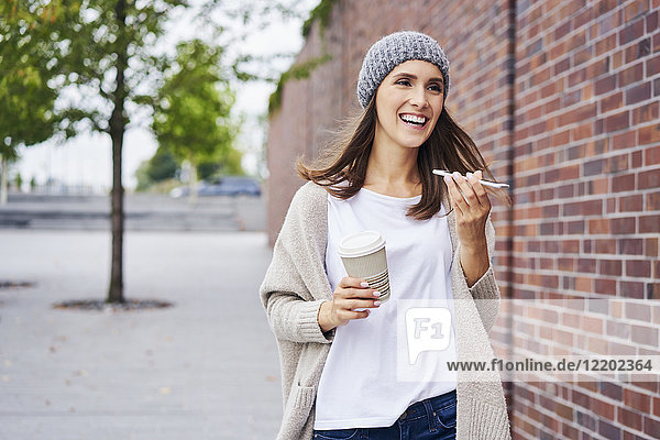 Porträt der glücklichen Frau mit Kaffee zum Telefonieren
