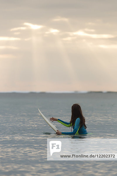 Indonesien  Bali  junge Frau mit Surfbrett im Wasser