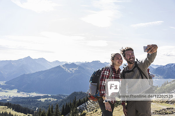 Austria  Tyrol  smiling young couple taking a selfie in mountainscape